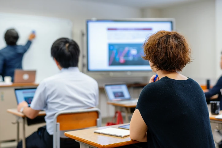 Estudantes em sala de aula tecnológica com professor escrevendo no quadro branco