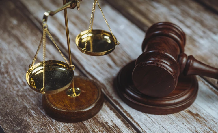 Balança da justiça dourada e martelo de juiz sobre mesa de madeira