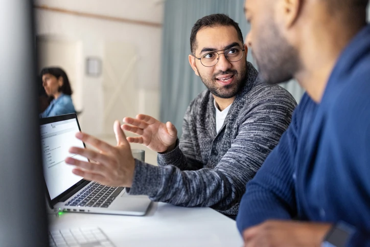 Colaboração profissional no ambiente de trabalho com equipe discutindo estratégias em um laptop