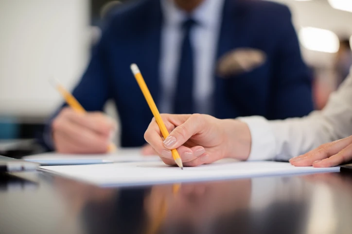 Profissionais corporativos focados escrevendo em papéis durante uma reunião de negócios importante no escritório