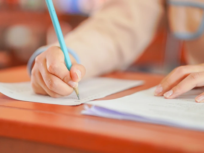 Close-up de estudante focado realizando atividades acadêmicas, escrita à mão e provas escolares para o sucesso educacional