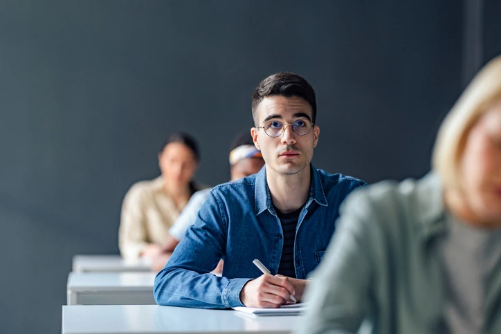Estudante universitário com óculos prestando atenção em aula na sala de aula