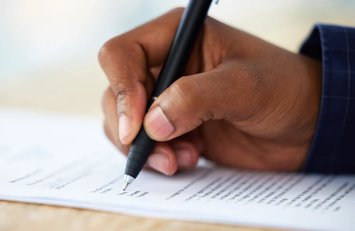 Mão de uma pessoa assinando um contrato importante em um documento oficial