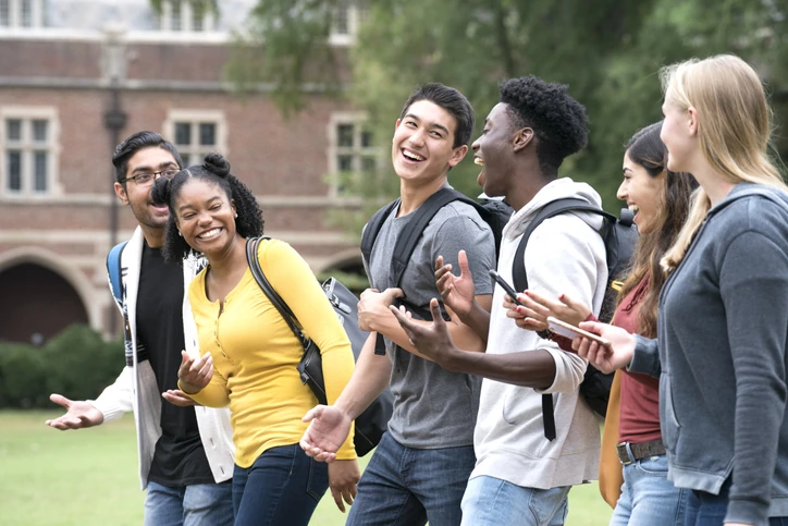 Grupo diversificado de estudantes universitários rindo e conversando no campus