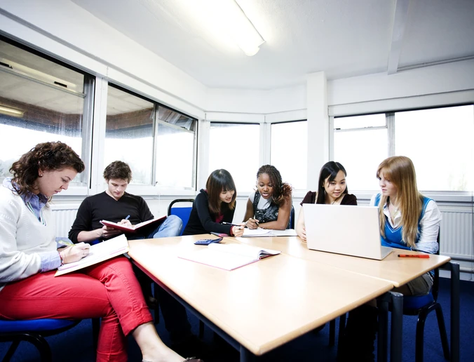 Grupo de estudantes diversos estudando juntos em uma sala de aula