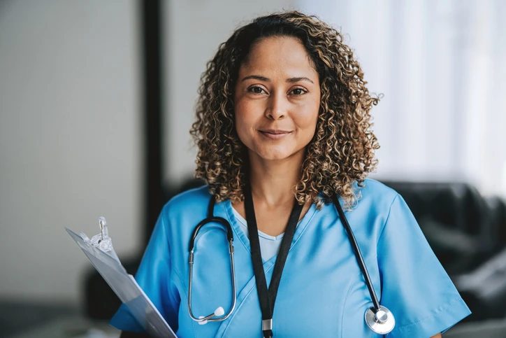 Profissional de enfermagem qualificada pronta para atendimento médico em ambiente hospitalar ou clínico Enfermeira profissional sorrindo usando uniforme azul e estetoscópio com prancheta na mão