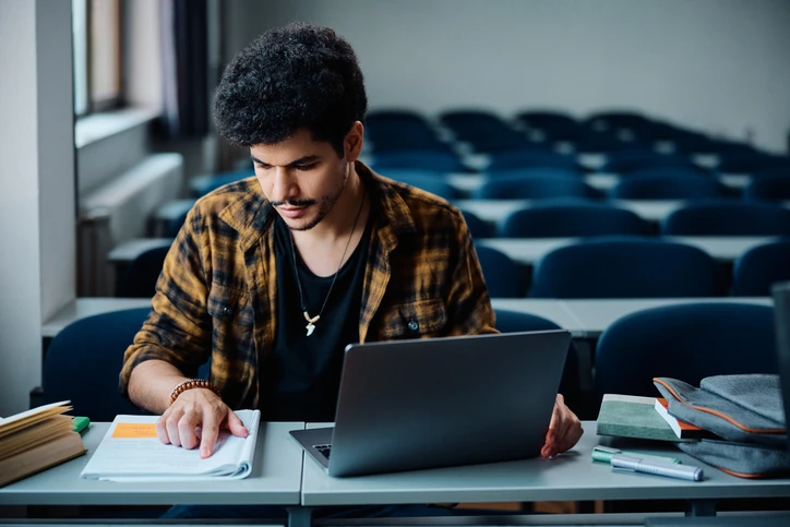 Estudante focado pesquisando alternativas após não passar no SiSU usando notebook em sala de aula