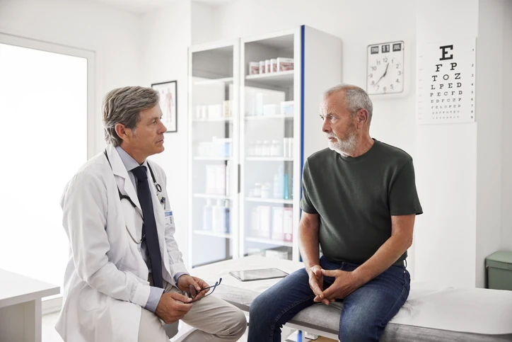 Médico conversando com paciente idoso em consultório clínico