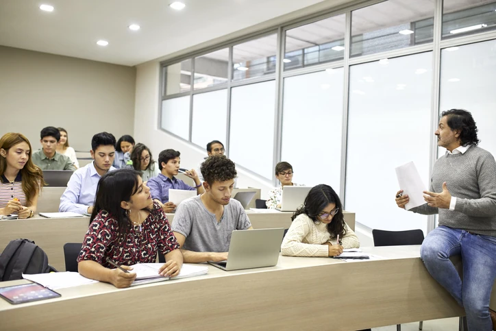 Professor ministrando aula em sala de aula universitária moderna com alunos atentos