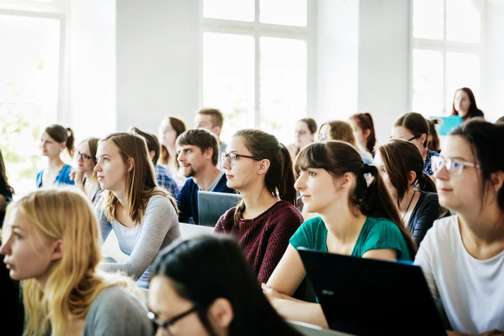 Grupo de estudantes universitários atentos durante uma aula em sala de aula iluminada
