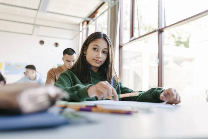 Estudante jovem em sala de aula moderna focada em seus estudos e atividades acadêmicas