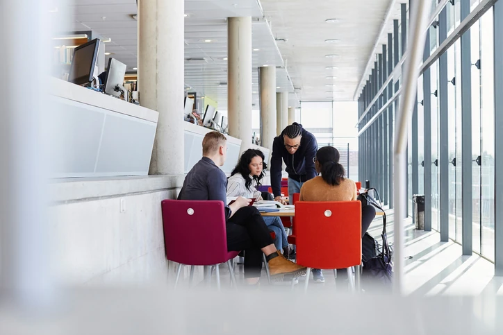 Grupo de estudantes universitários colaborando em um projeto de pesquisa em uma biblioteca moderna