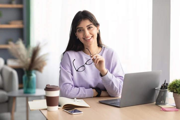https://estaticos.animaeducacao.com.br/medias/20260121165141/GettyImages-1351342379.webp Jovem profissional sorridente utilizando notebook para trabalho remoto ou estudos online em um escritório moderno e iluminado