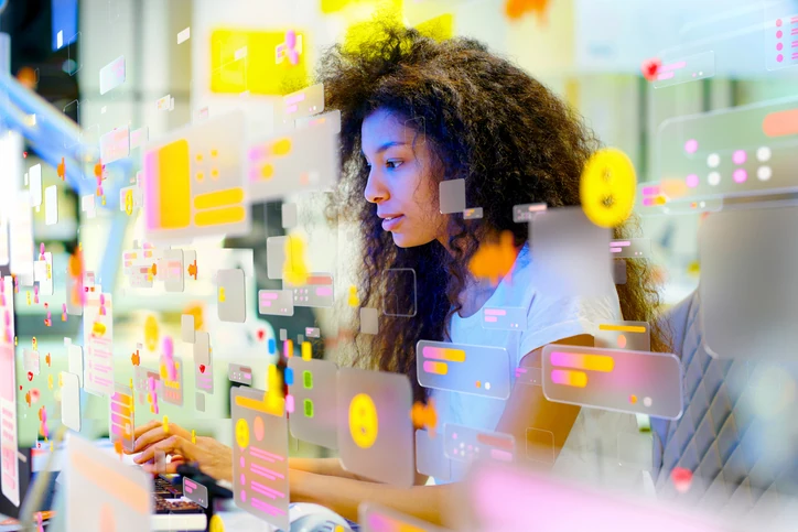 Mulher jovem trabalhando em um computador com interface de realidade aumentada e ícones digitais flutuantes