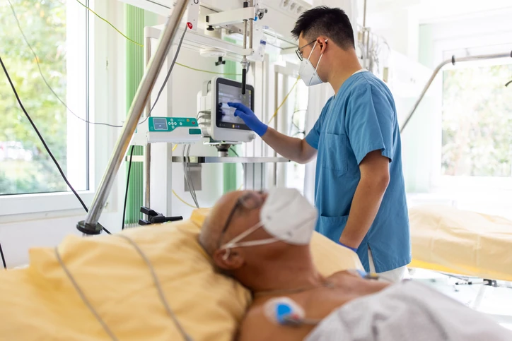 Enfermeiro ajustando equipamentos médicos em paciente internado em hospital com suporte de vida