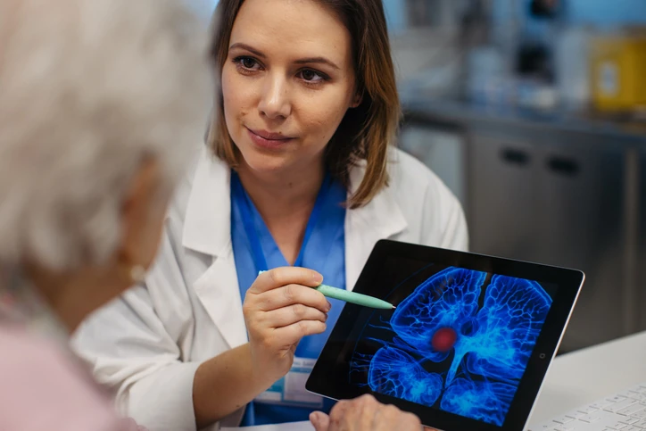 Médica mostrando exame de imagem cerebral em tablet para paciente idosa