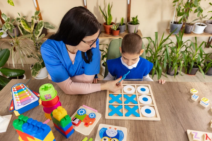 Terapeuta infantil jogando jogo da velha com criança em sessão de terapia educativa