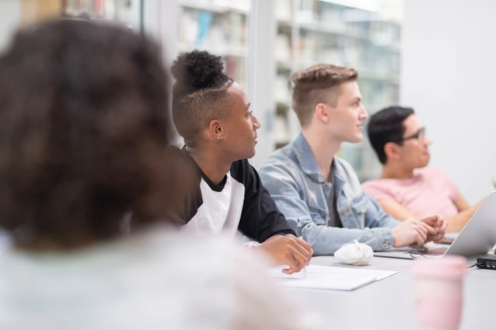 Estudantes universitários focados em uma aula prática com notebooks e materiais de estudo em um ambiente acadêmico colaborativo