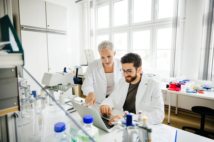 Dois cientistas trabalhando juntos em um laboratório de pesquisa usando um laptop