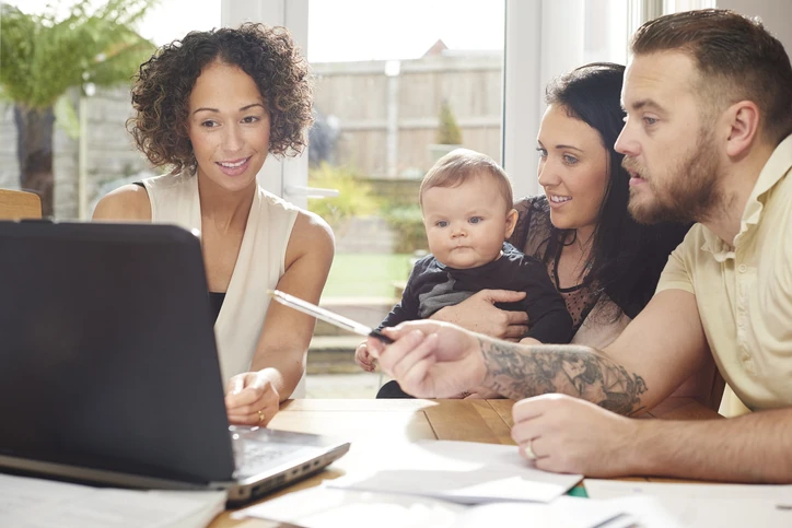 Consultora financeira conversando com um casal e seu bebê sobre planejamento familiar no notebook