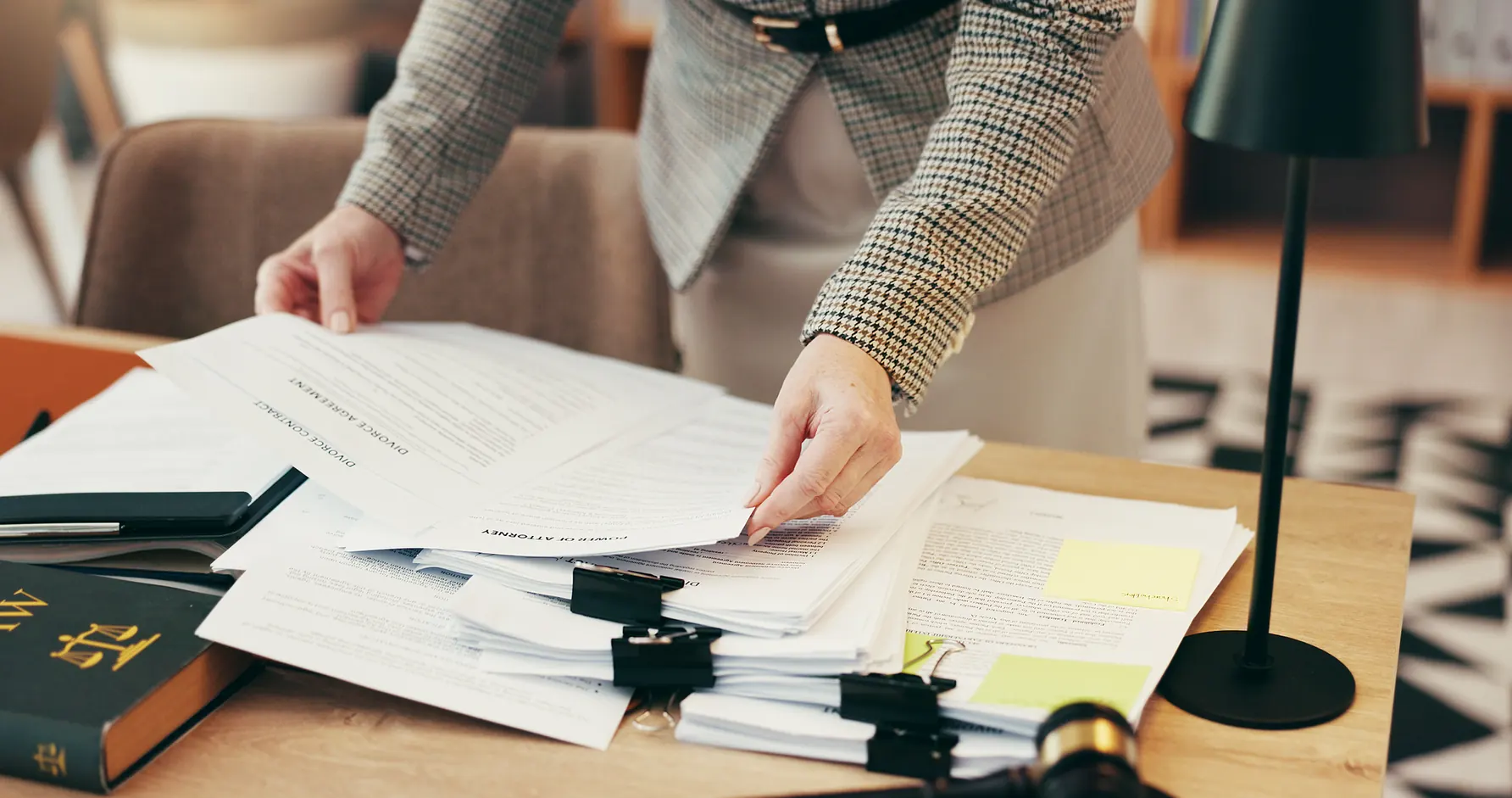 Advogada organizando documentos jurídicos e contratos de divórcio em uma mesa de escritório