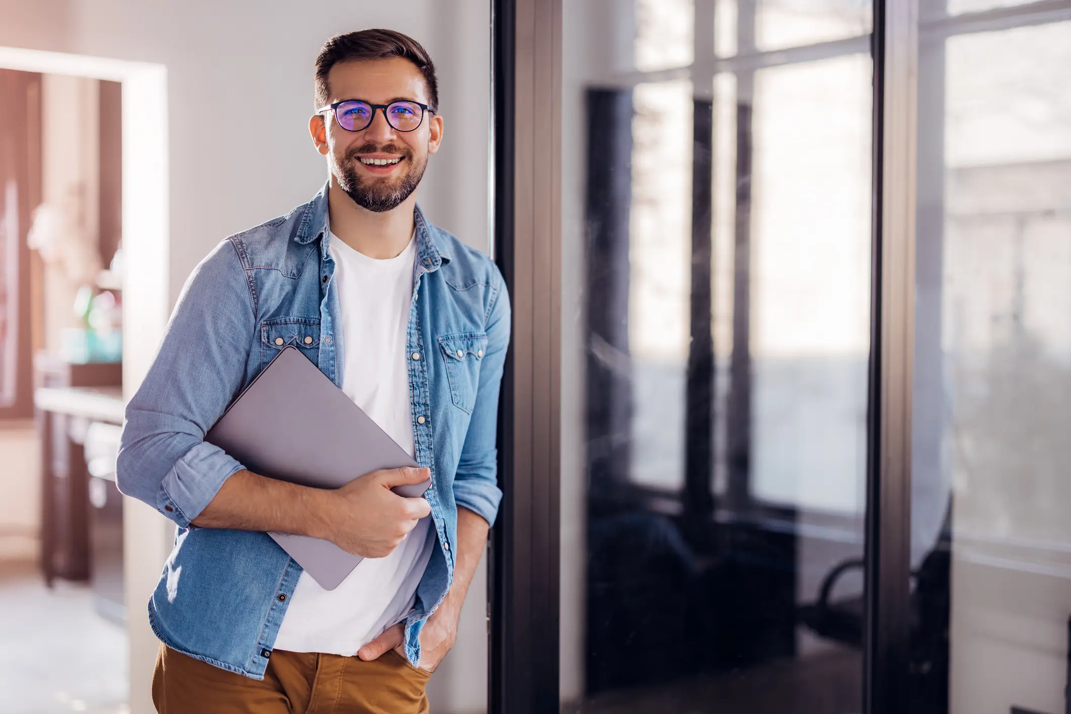 Jovem profissional sorridente segurando um notebook em um ambiente de escritório moderno