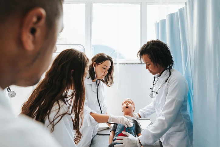 Estudantes de medicina praticando técnicas de reanimação em um boneco de simulação clínica