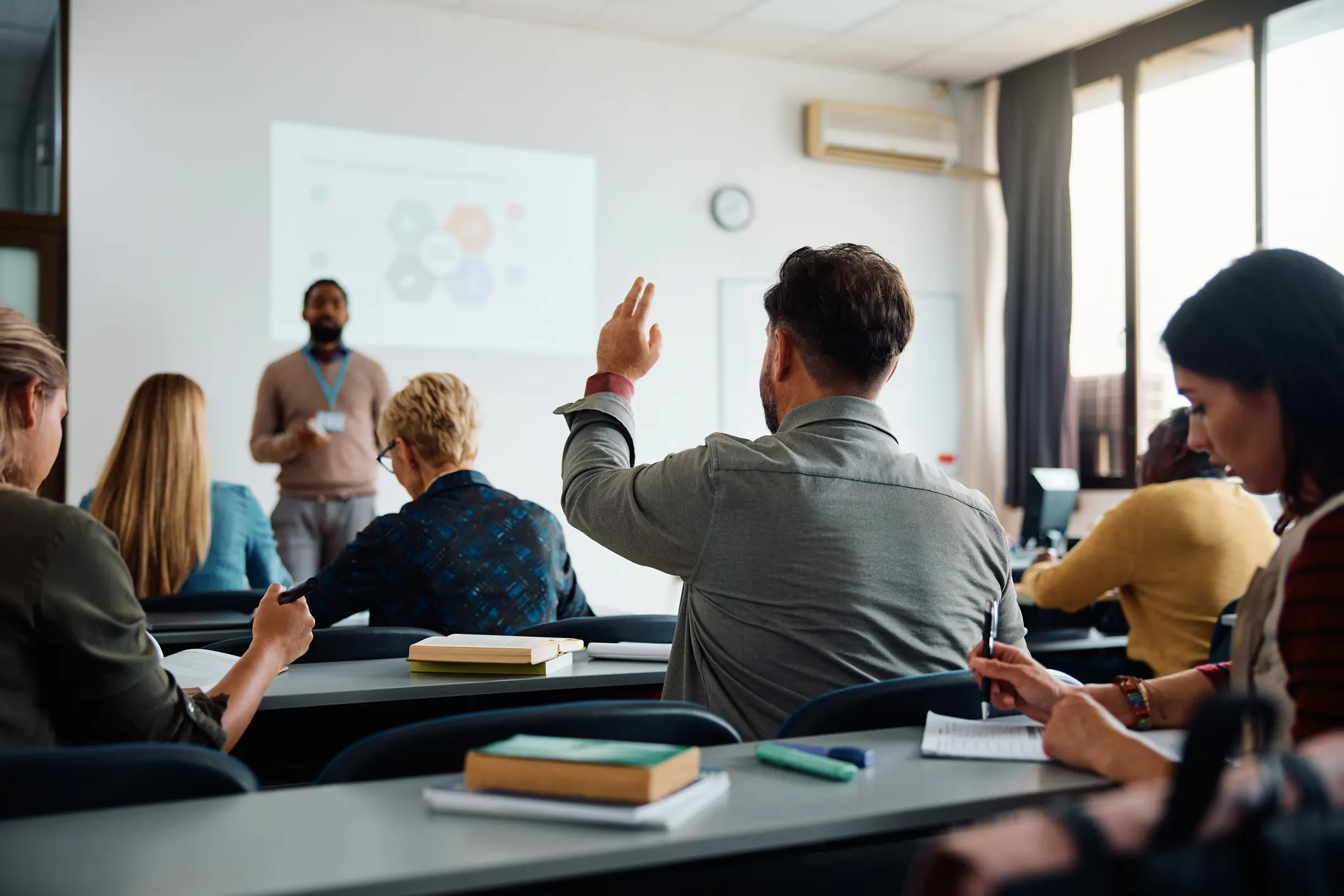 Estudante levantando a mão em sala de aula durante palestra sobre como entrar na faculdade