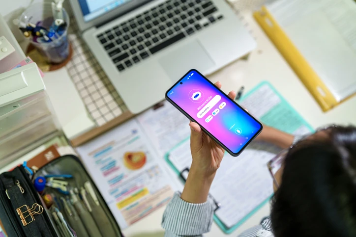 Estudante utilizando aplicativo de chatbot com inteligência artificial em smartphone durante estudos