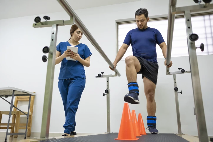 https://estaticos.animaeducacao.com.br/medias/20260225115925/GettyImages-2164983374.webp Paciente realizando exercícios de fisioterapia e reabilitação motora com auxílio de profissional especializado em clínica