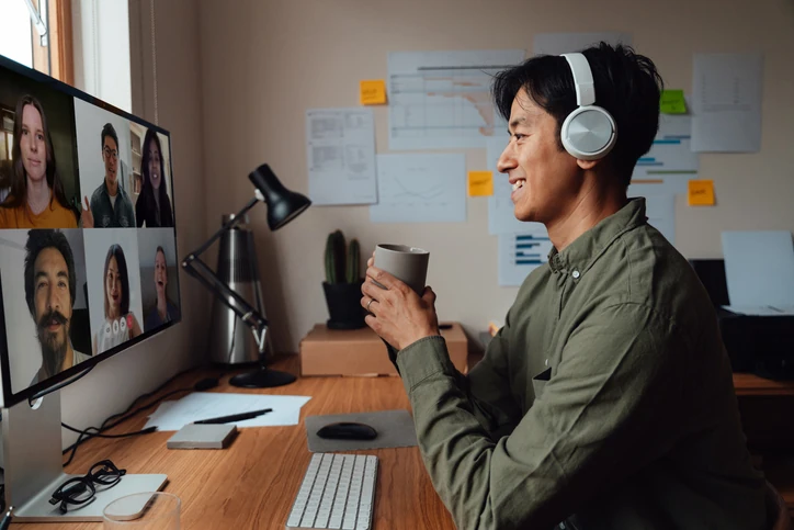 Profissional realizando trabalho remoto e participando de reunião virtual com equipe via chamada de vídeo no escritório doméstico Homem asiático trabalhando em home office participando de uma reunião por videoconferência com colegas em seu computador