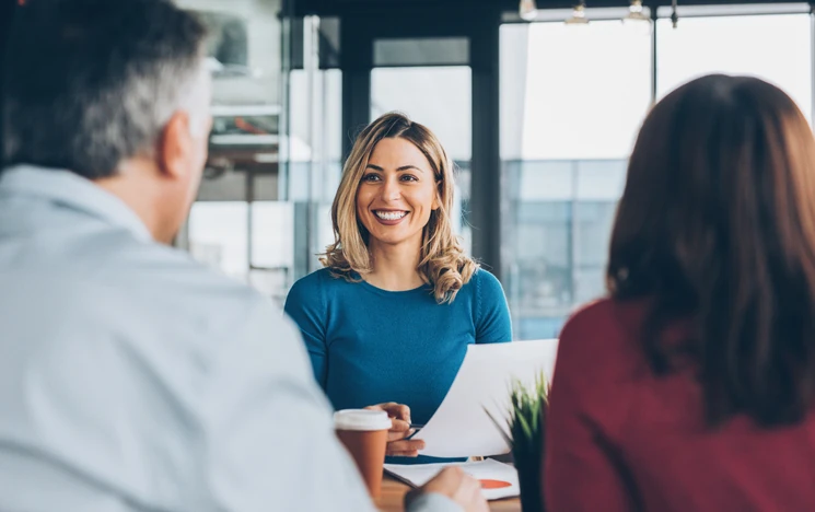 Mulher sorridente participando de uma reunião profissional com colegas no escritório