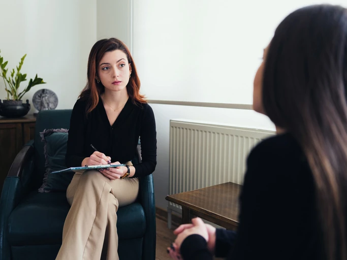 Sessão de psicoterapia profissional com psicóloga atenta fazendo anotações durante atendimento clínico