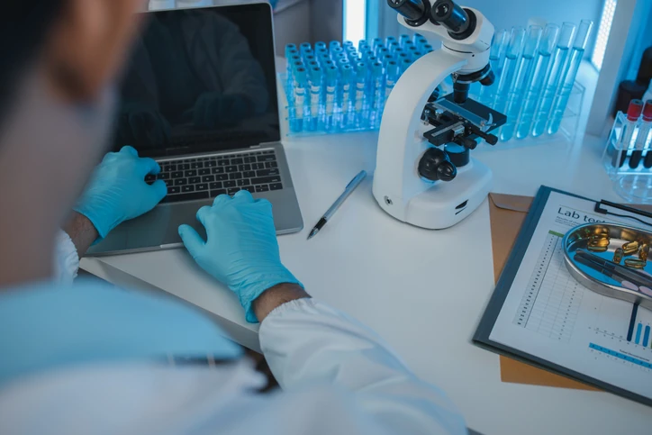 Cientista utilizando laptop e microscópio para análise de dados e testes em ambiente laboratorial profissional Cientista trabalhando em laboratório com laptop, microscópio e amostras