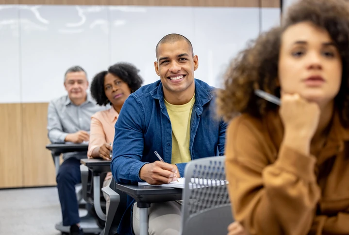 Estudantes adultos em uma sala de aula moderna focados em aprendizado e desenvolvimento profissional contínuo