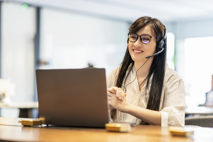 Atendente ou profissional de suporte realizando atendimento remoto via videochamada no computador com headset