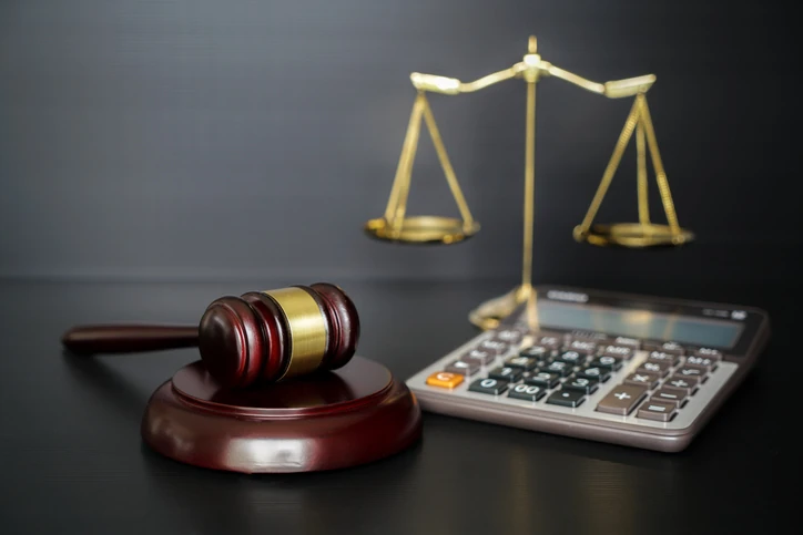 Simbolismo do direito e justiça com martelo de juiz balança e cálculos financeiros para advocacia