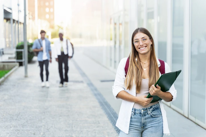 Estudante universitária sorridente segurando pasta no campus