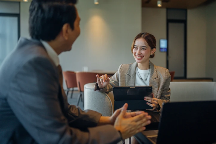 Profissionais conversando e trabalhando em equipe com tablet e notebook em um ambiente corporativo moderno e produtivo Homem e mulher de negócios em reunião colaborativa em escritório moderno