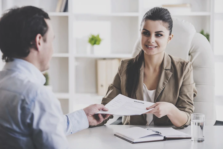 Mulher entregando currículo durante entrevista de emprego em um escritório profissional