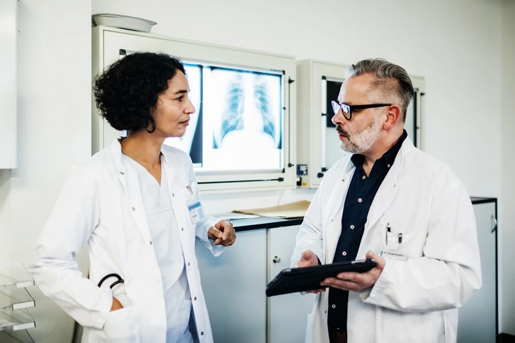Médicos discutindo diagnóstico médico em frente a uma tela de raio-x