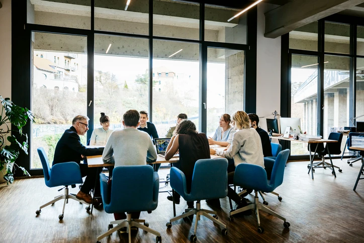 Equipe diversa trabalhando em colaboração durante uma reunião de negócios em um escritório moderno com iluminação natural Equipe de profissionais diversos em reunião de negócios colaborativa em escritório moderno com janelas amplas