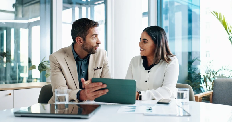 Colaboração profissional e trabalho em equipe corporativa usando tecnologia digital em ambiente de escritório Dois profissionais de negócios conversando e colaborando em um tablet dentro de um escritório moderno