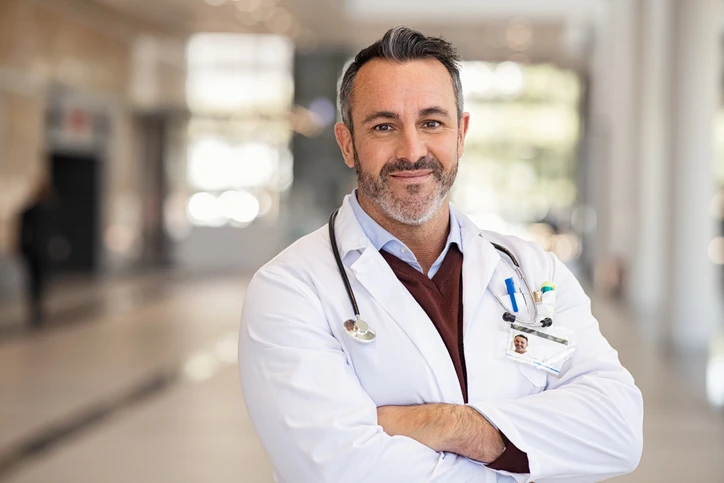 Médico profissional sorridente com jaleco e estetoscópio no hospital
