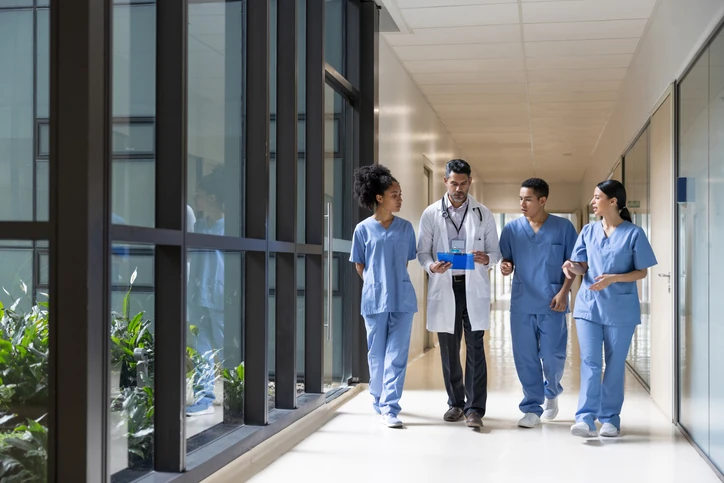 Equipe médica multidisciplinar caminhando em corredor de hospital
