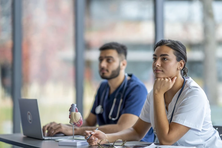 Estudantes de medicina estudando com modelo anatômico de coração em sala de aula