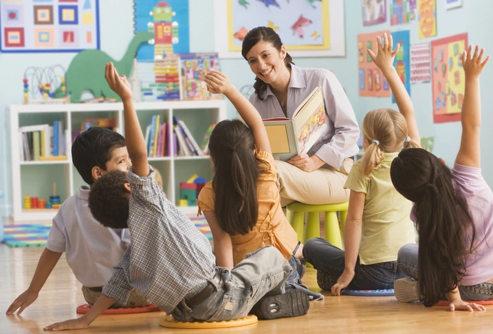 Professora engajada lendo história para alunos em ambiente de educação infantil inclusivo e interativo