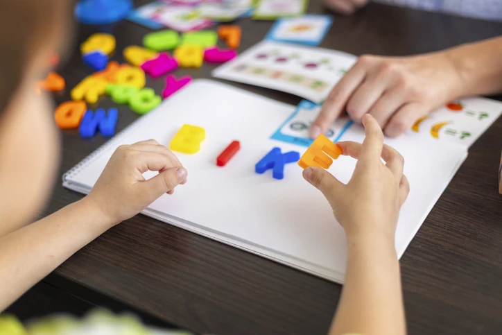 Criança aprendendo a formar palavras com letras de plástico coloridas em uma atividade educativa