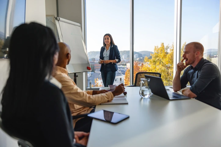 Mulher fazendo apresentação em reunião corporativa para equipe em escritório moderno