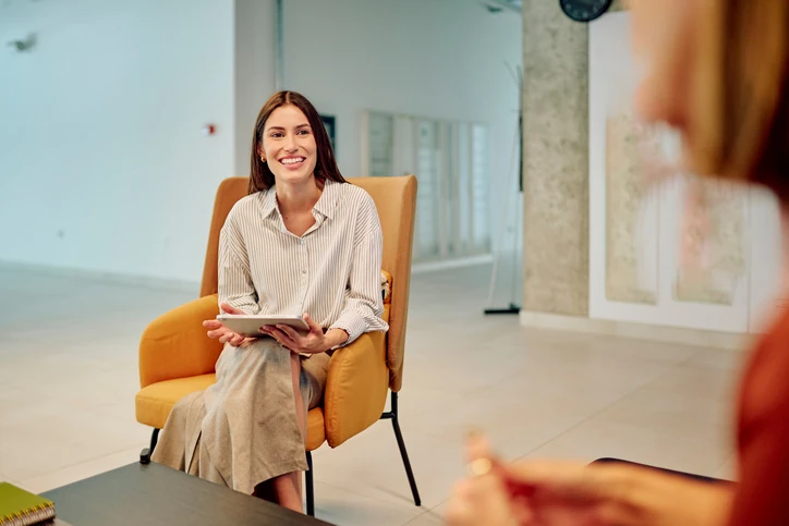 Profissional sorridente participando de reunião de trabalho descontraída em um ambiente corporativo moderno